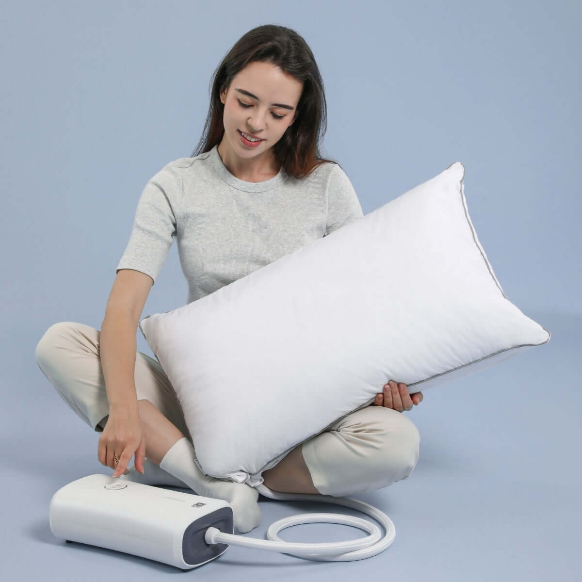 Woman demonstrating inflatable pillow with pump system on a blue background