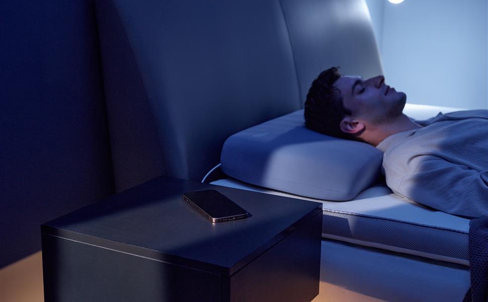 Sleeper resting on the Nitetronic A1 smart pillow with a phone on the nearby nightstand