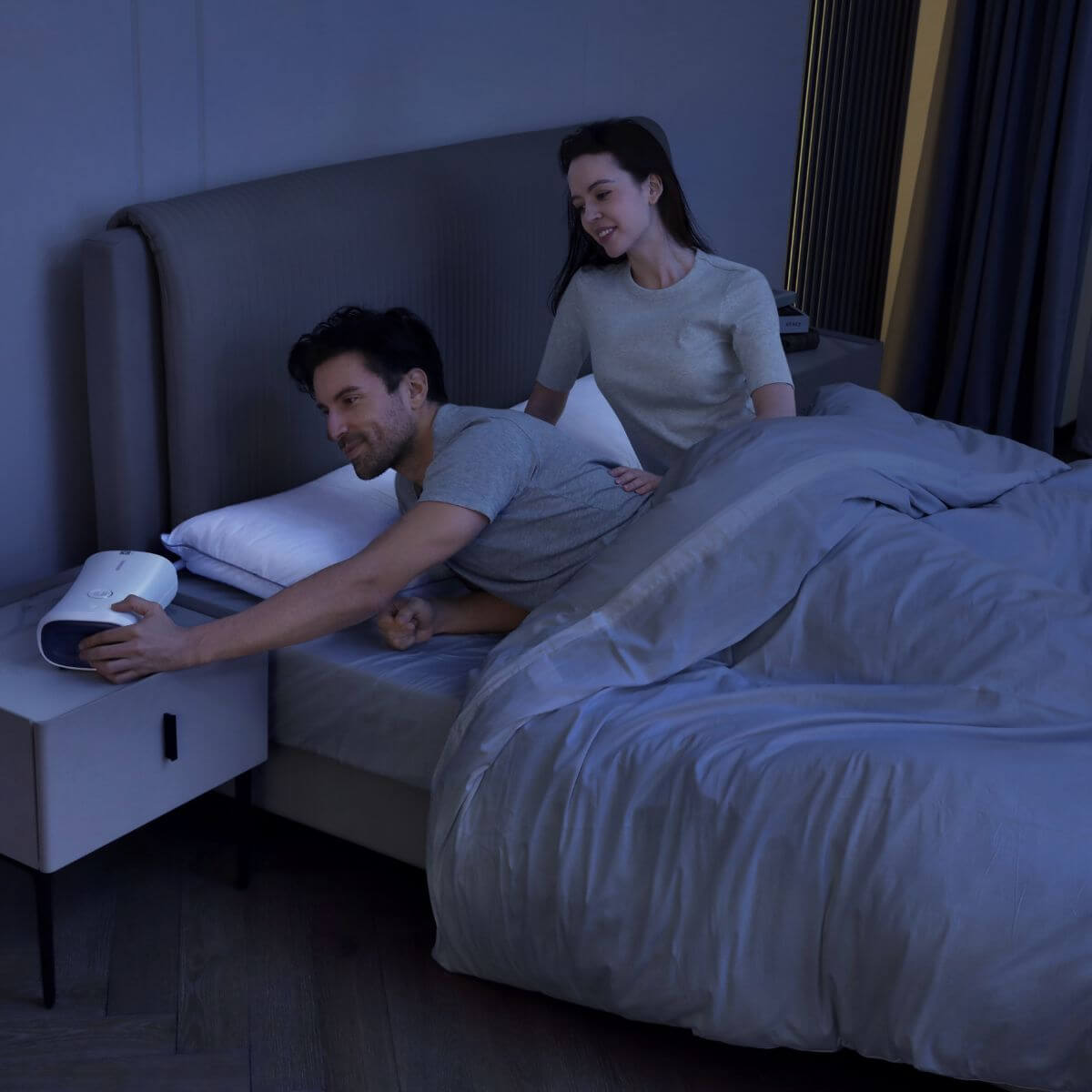Couple using the Nitetronic anti-snoring pillow in a bedroom setting to reduce snoring and improve sleep quality.