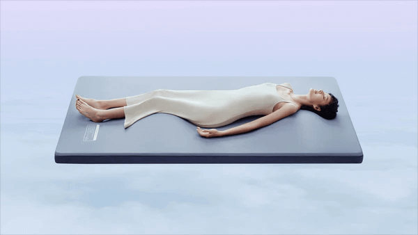 Woman relaxing on Nitetronic smart mattress pad for enhanced sleep quality.