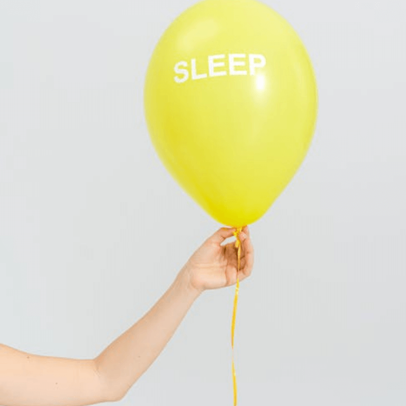 Yellow balloon with the word 'SLEEP,' representing sleep improvement tips, held by a hand.