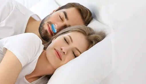 Couple sleeping peacefully, man using Nitetronic Anti-Snore Pillow Z1 to combat snoring issues.