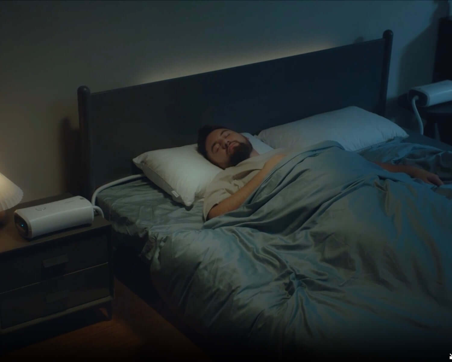 Person sleeping peacefully with a sleep apnea pillow in a dimly lit bedroom, highlighting improved sleep quality.