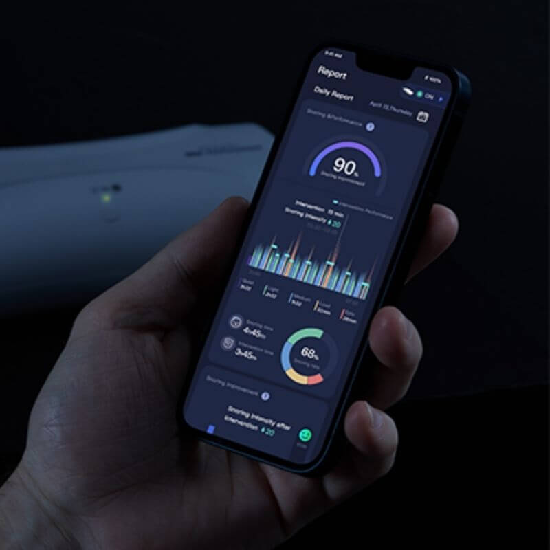Person holding smartphone displaying anti-snoring app with sleep tracking data and graphs.