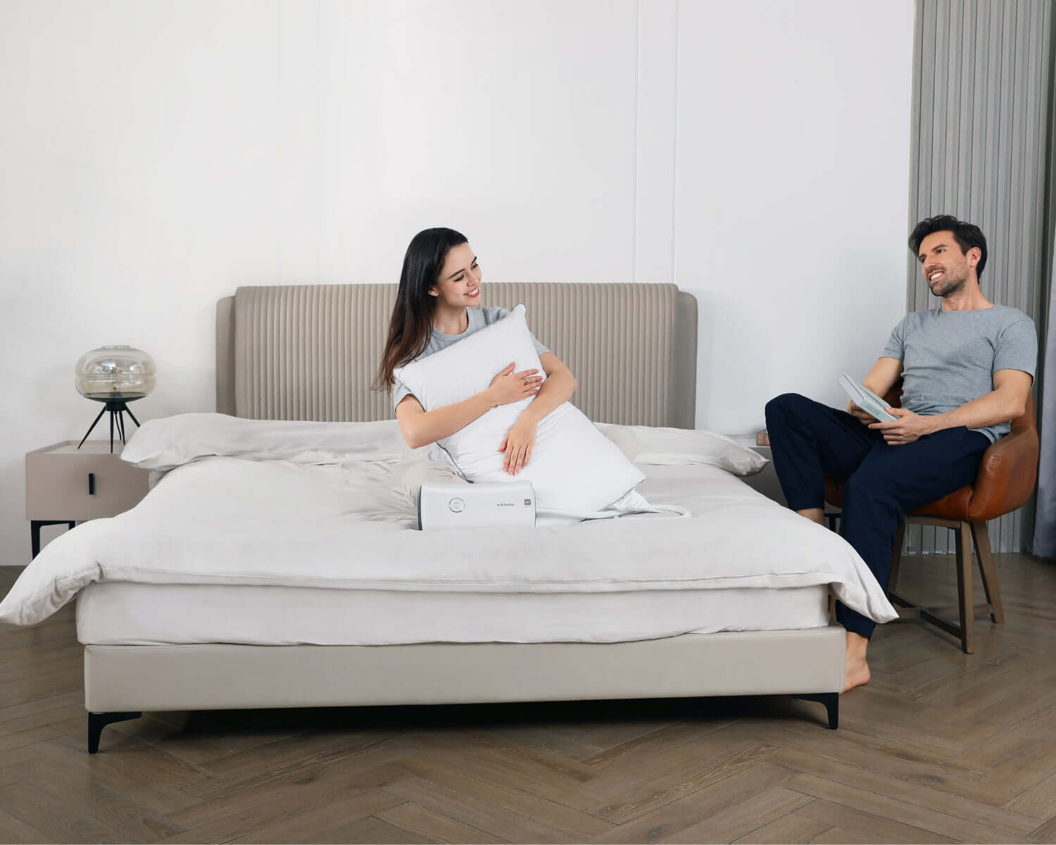 Couple in bedroom discussing snoring solutions with the Nitetronic Z6 Snore-Reducing Pillow on the bed.
