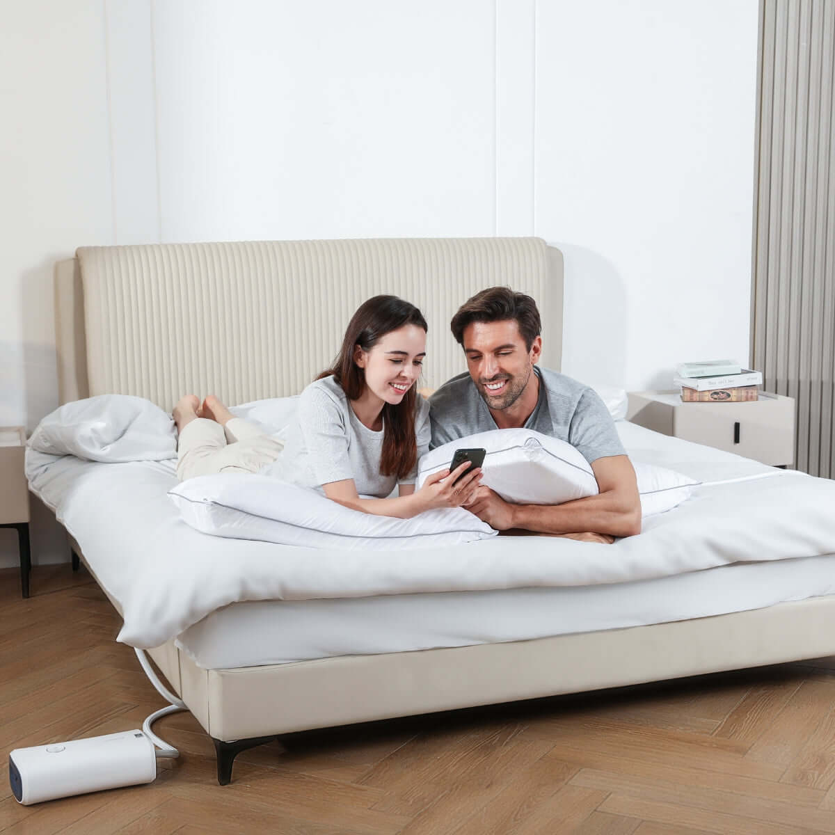 Couple testing smart anti-snore pillow for sleep apnea, lying on modern bed with device