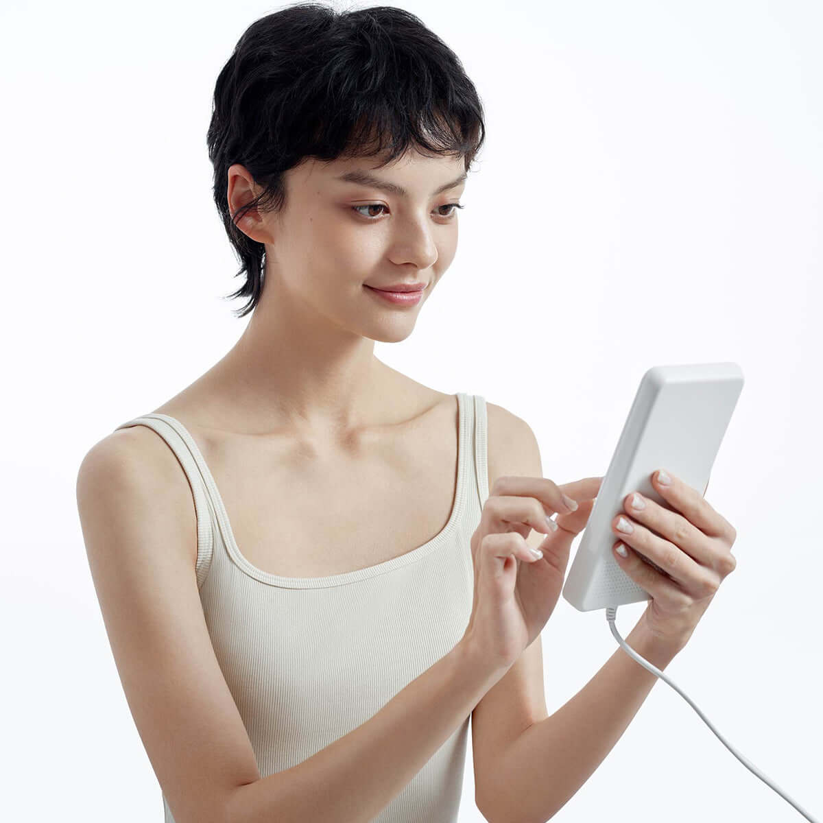 Person using a white electronic device connected by a cord.