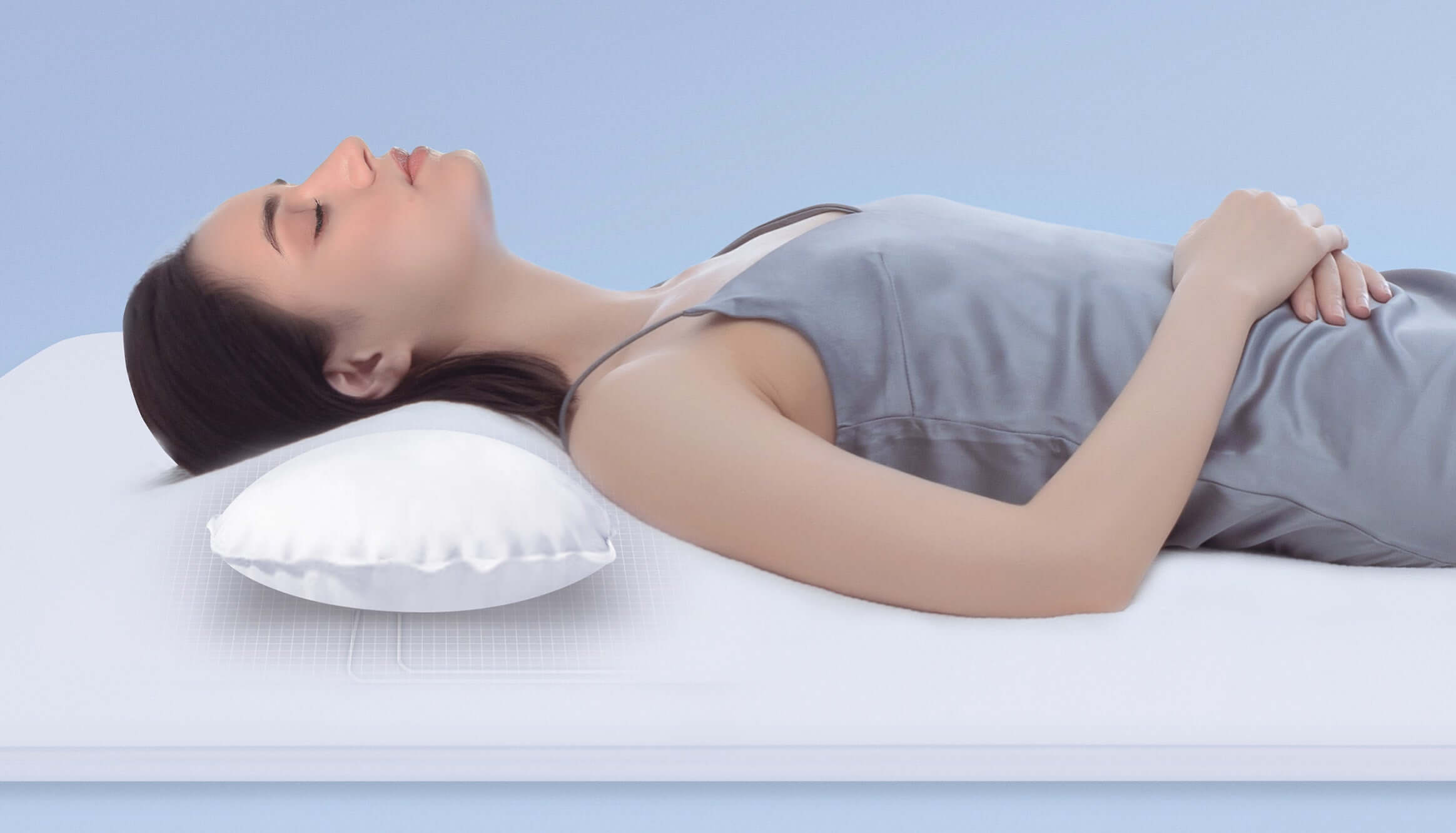 Woman lying on memory foam mattress with white pillow for neck support and comfort.
