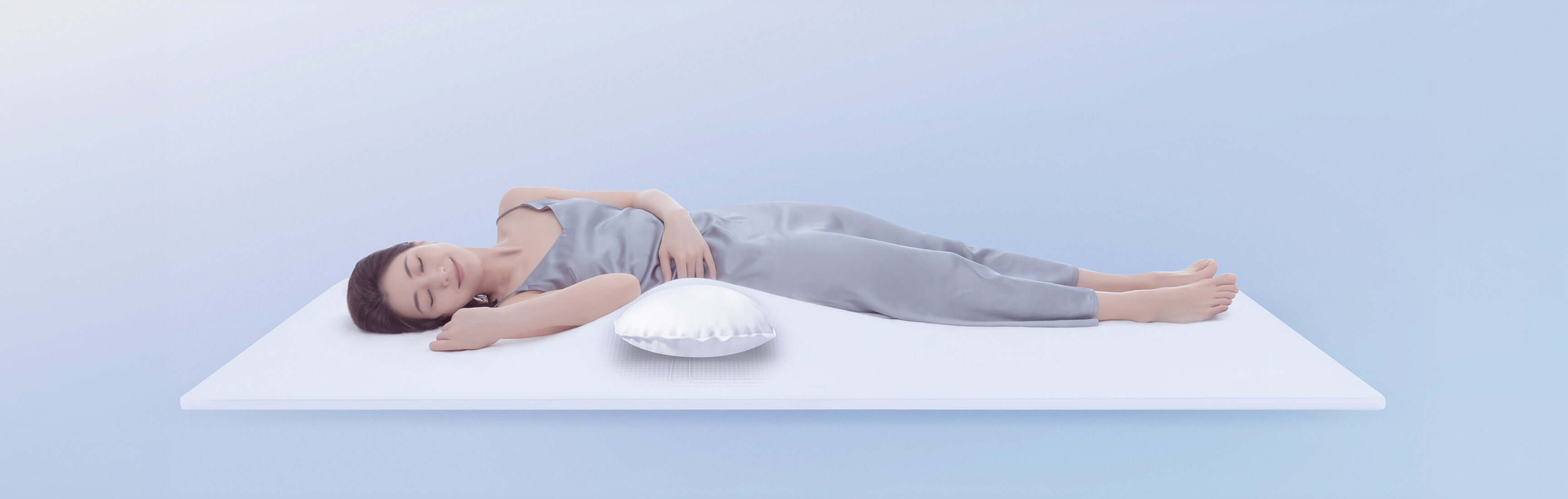 Person sleeping comfortably on a white mattress with a pillow, wearing gray pajamas, set against a light blue background.