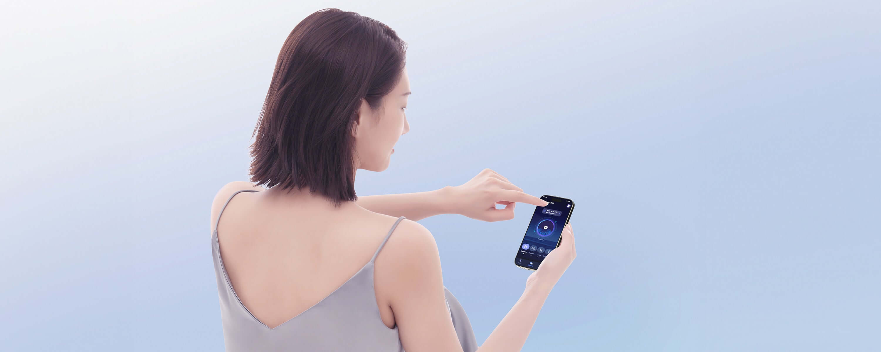 Woman using a smartphone with a blue screen background, wearing a light gray sleeveless top.
