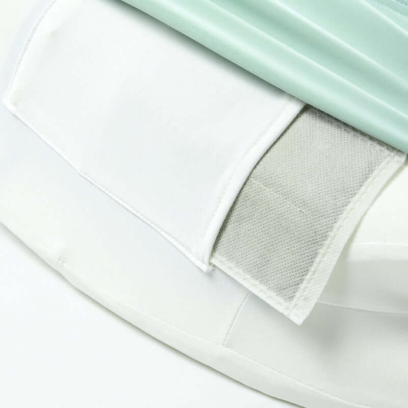 Close-up of a white velcro fastener on a mattress cover with mint-colored padding.