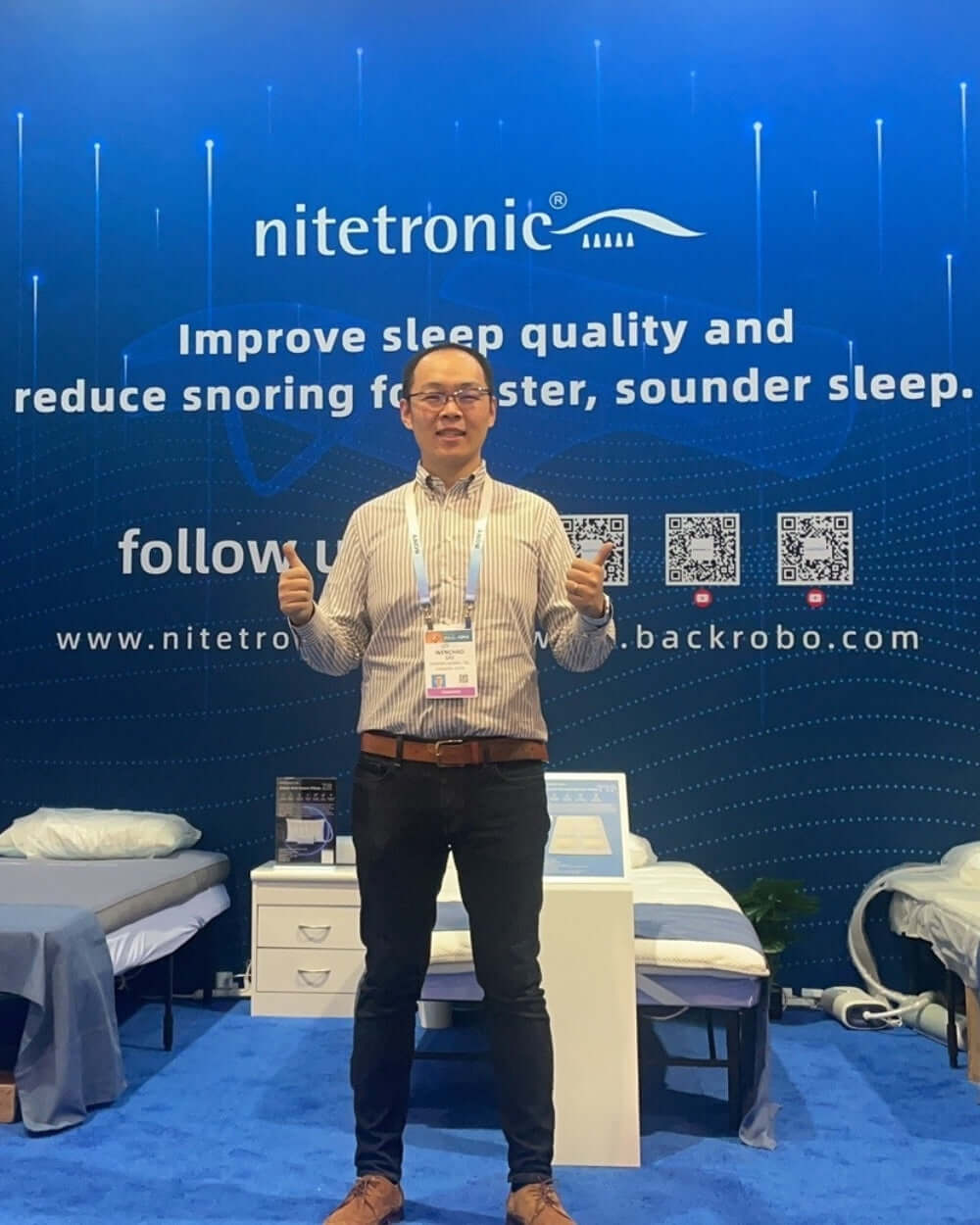 Person standing in front of Nitetronic display booth promoting sleep quality and snoring reduction products at an event.