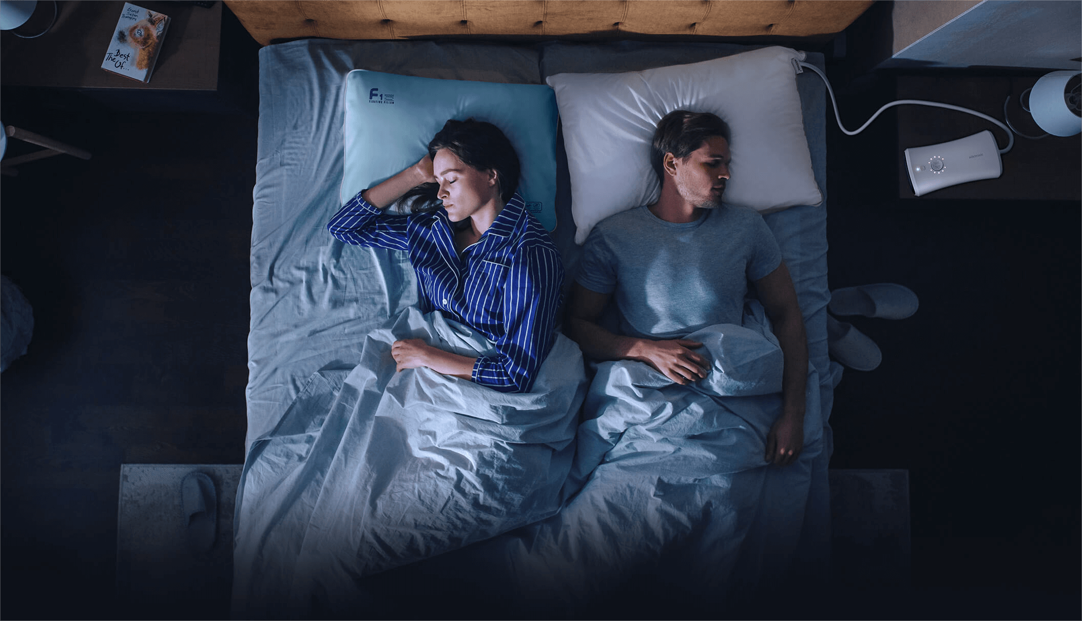 Couple sleeping in bed with adjustable pillows and nightstand gadgets for optimal sleep environment.