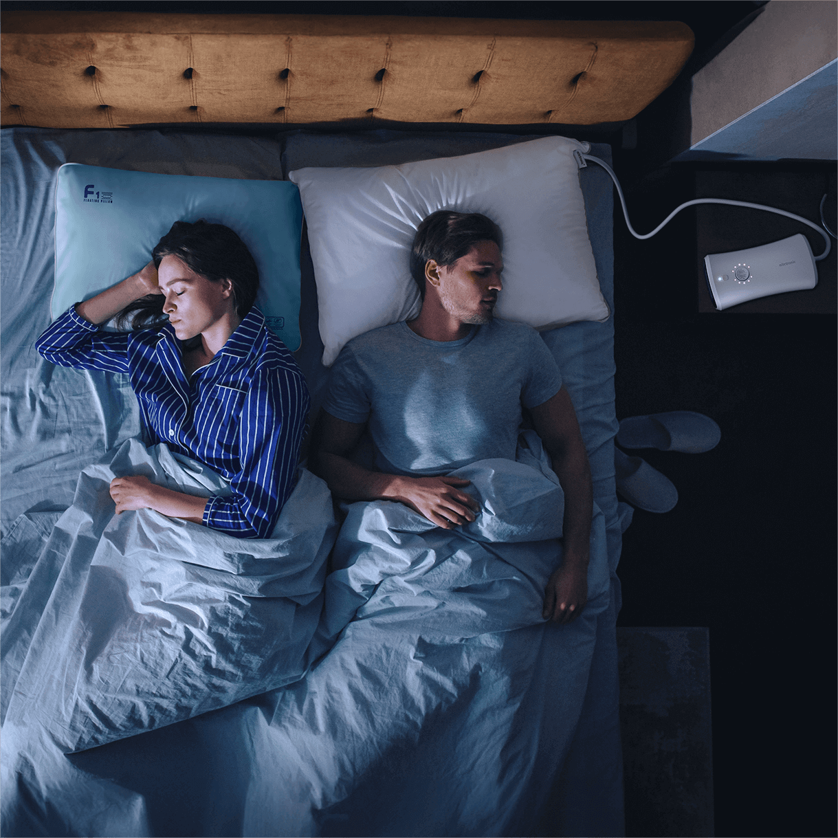 Couple sleeping in bed with medical device on nightstand, enhancing sleep quality.