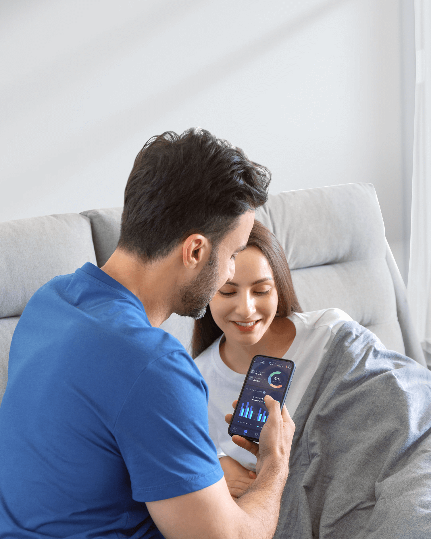 Couple using smartphone with Nitetronic Z6 Smart Anti-Snore Pillow, adjusting settings for personalized sleep experience.