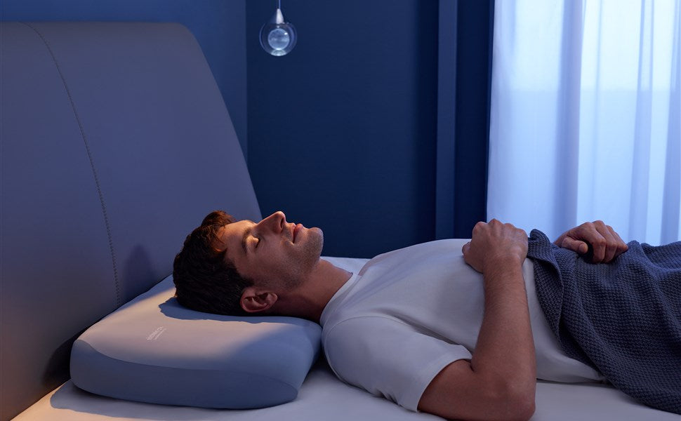 Back sleeper resting on a real Nitetronic A1 AI anti-snore pillow in a blue bedroom