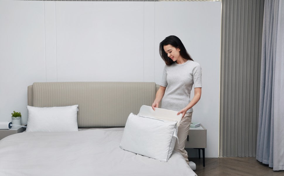 Person preparing a Nitetronic Z6 smart pillow on a bed